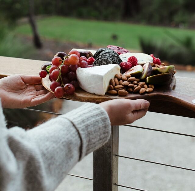 Femme qui tient un plateau de fruits et de fromages